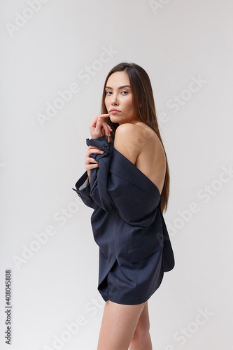 portrait of young attractive asian woman with long hair in blue suit isolated on studio background. skinny pretty female posing with naked shoulder. model tests of beautiful lady