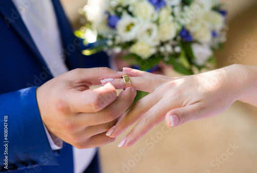 The groom puts a gold wedding ring on the bride's finger