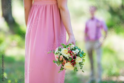 A bouquet of fresh flowers in hands nesta in a pink dress close-up photo