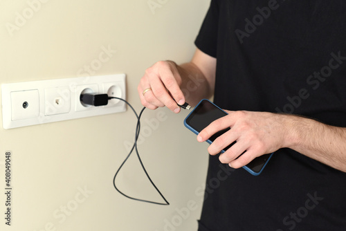 Hand holding smartphone and preparing for charging