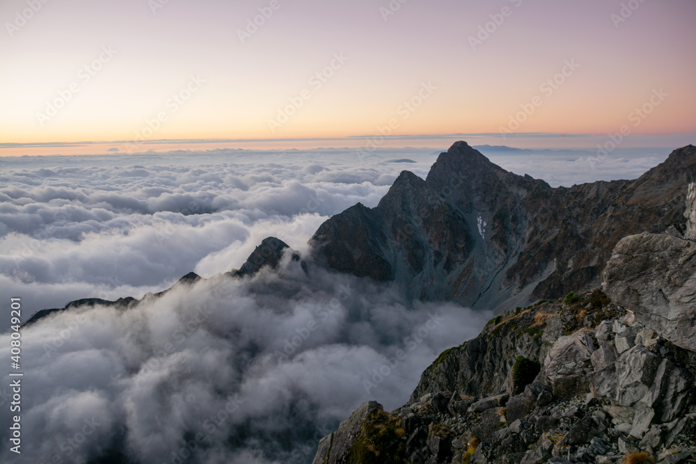 Obraz premium 信州北アルプス、北穂高岳山頂直下北穂高小屋より、眼下に広がる雲海、前穂高岳、奥穂高岳、マジックアワー。朝焼け夜明け。