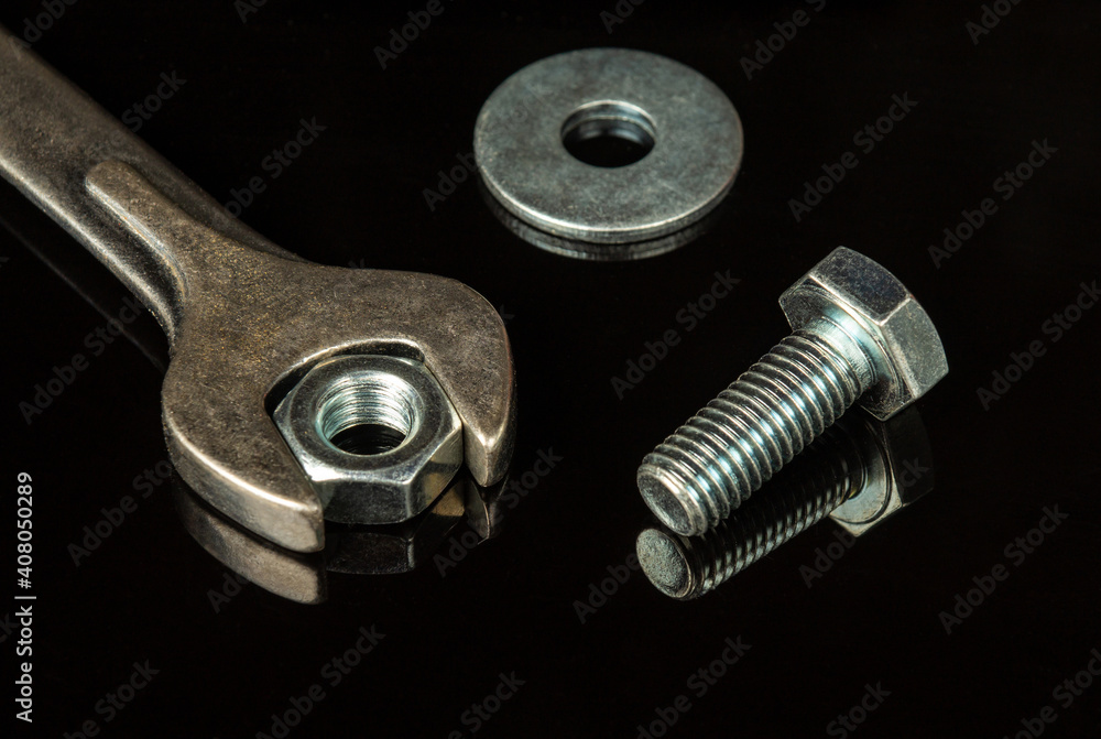 Wrench with nut and bolt on black background. The idea of connecting spare parts in construction Wrench with nut and bolt on black background. The idea of connecting spare parts in construction