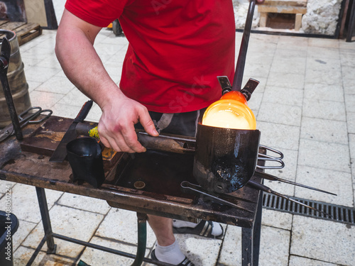 Artist glass blowing process. The glassblower master with co-workers are creating an amazing piece of art from molten glass