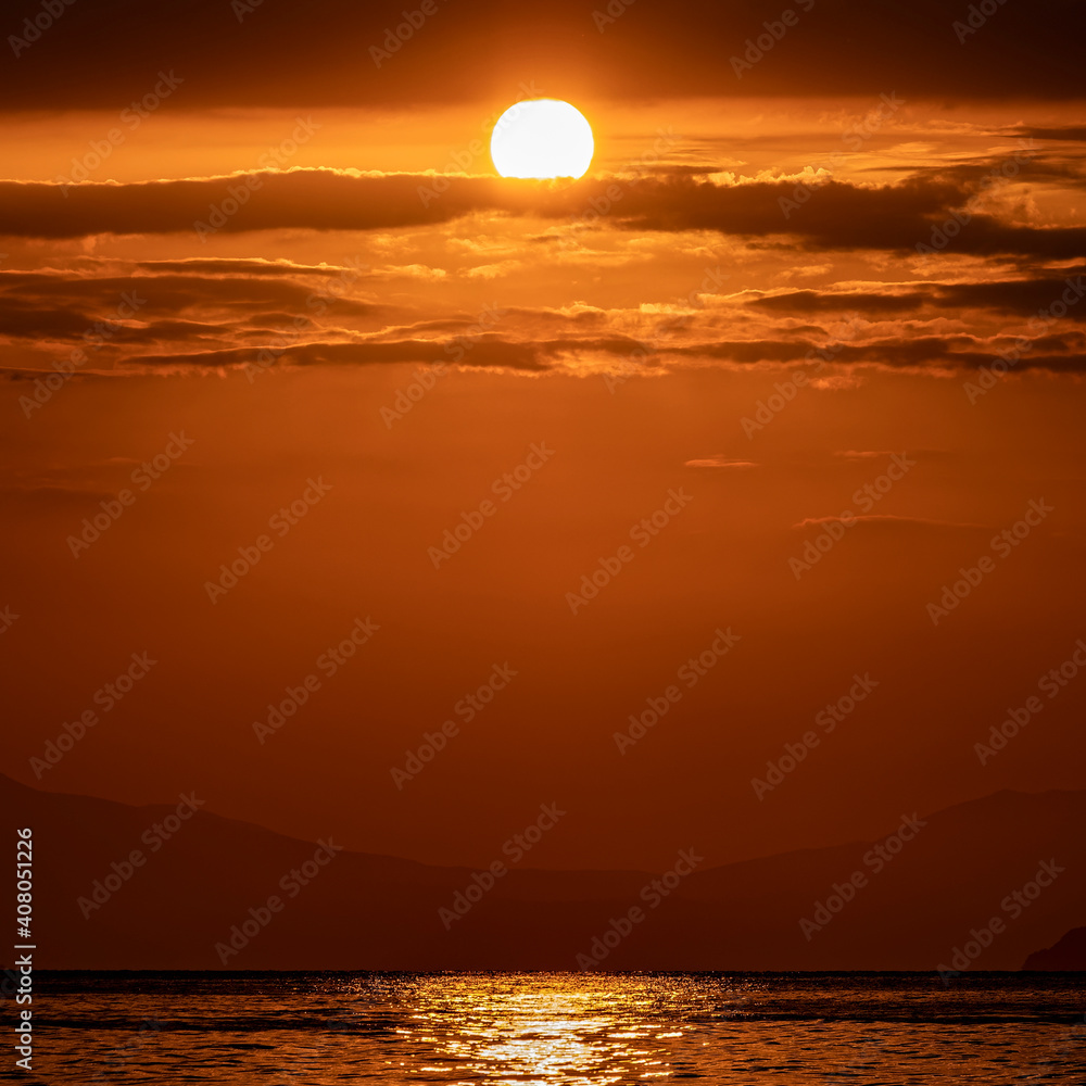 orange fiery sunrise sky with some clouds over calm sea, nature background.