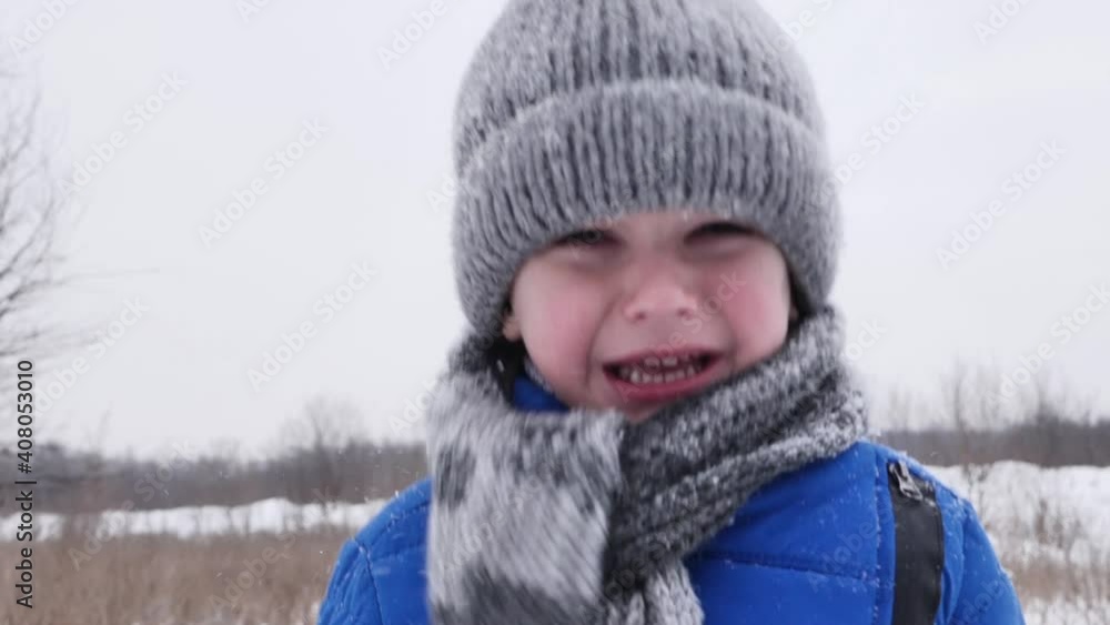 Little boy in the cold cries in the snow-covered forest in winter. Slow motion Little boy in the cold cries in the snow-covered forest in winter. Slow motion