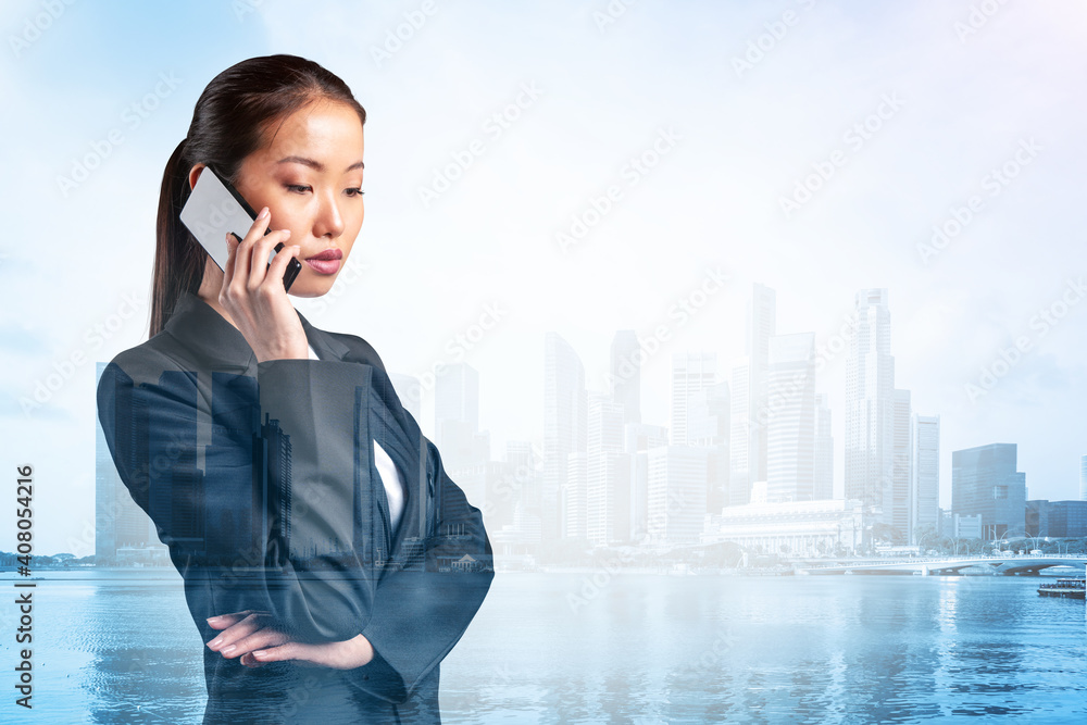 Prosperous astonishing young Asian business woman in suit pensively talking phone, Singapore cityscape. The concept of consultants as problem solvers. Investment fund. Double exposure. Prosperous astonishing young Asian business woman in suit pensively talking phone, Singapore cityscape. The concept of consultants as problem solvers. Investment fund. Double exposure.