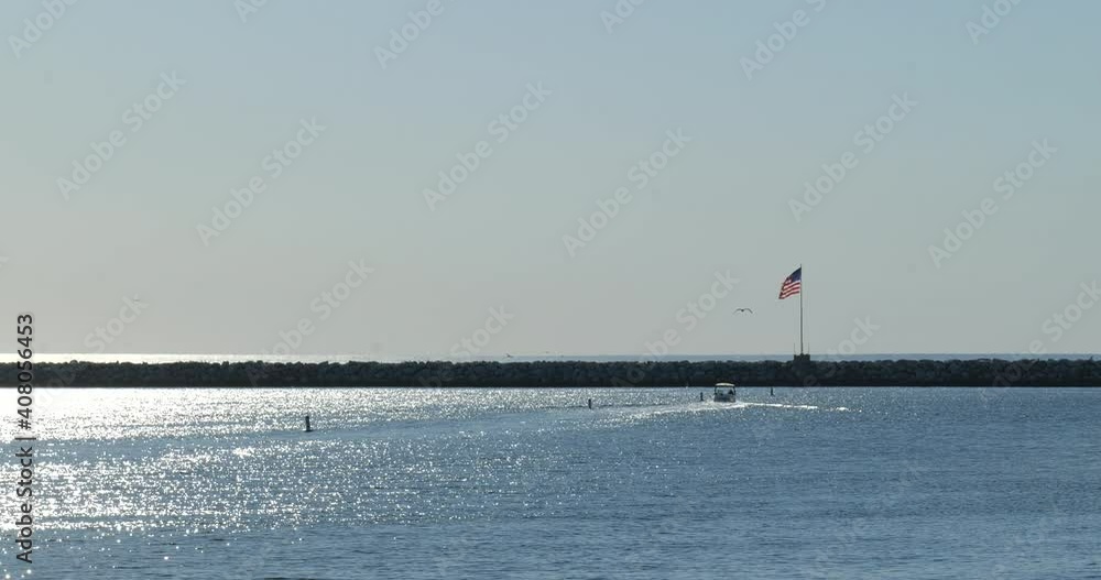 Boat traveling into the sunset with an American Flag blowing on the breakwater Boat traveling into the sunset with an American Flag blowing on the breakwater