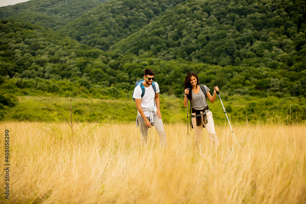 Smiling couple walking with backpacks over green hills Smiling couple walking with backpacks over green hills
