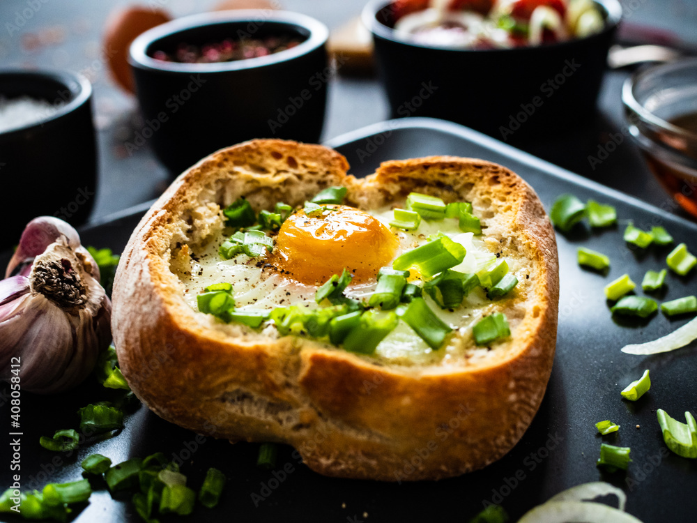 Continental breakfast - sunny side up egg in baked bun with cheese and vegetable salad on black Continental breakfast - sunny side up egg in baked bun with cheese and vegetable salad on black