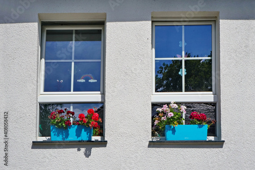 Two windows on a white wall in hot summer with blue flower girls.