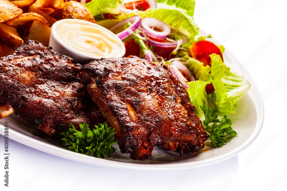 Tasty roasted ribs with baked potatoes vegetables on white background
