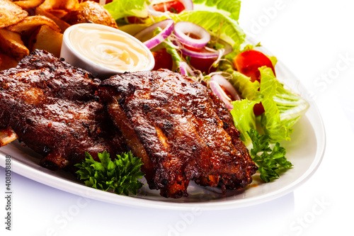 Tasty roasted ribs with baked potatoes vegetables on white background 