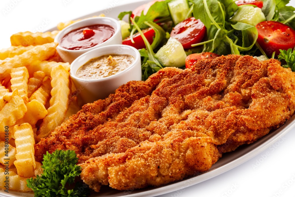 Breaded fried pork chop, French fries and vegetables on white background
Breaded fried pork chop, French fries and vegetables on white background