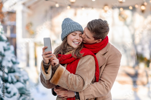 Happy couple taking selfie by smartphone over winter background