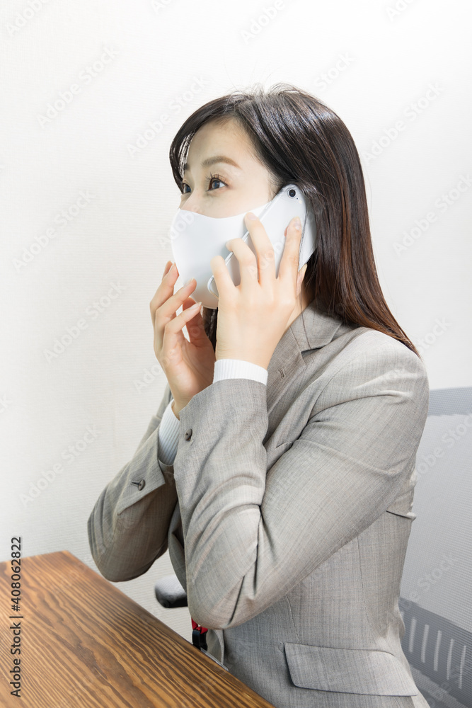 Surprised woman wearing a mask on the phone at work Surprised woman wearing a mask on the phone at work