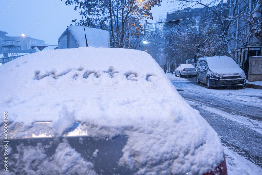 town covered by snow and winter handwriting on window of a car in winter time