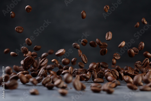 Levitation coffee beans. Grains of roasted coffee falling on gray stone background. Shallow depth of field 
