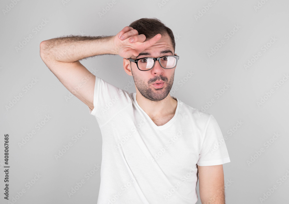 A grown bearded guy wipes his forehead with his hand, making a fu gesture, expressing relief while standing against a gray wall. The man is happy that he has prevented a huge catastrophe. A grown bearded guy wipes his forehead with his hand, making a fu gesture, expressing relief while standing against a gray wall. The man is happy that he has prevented a huge catastrophe.