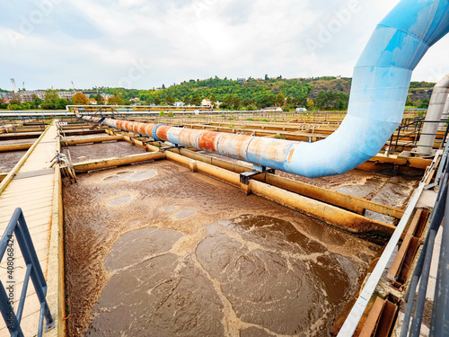 Pipe and walk bridge above waste water pool. Huge tank for residual rotting bacterias in sludge.  photo