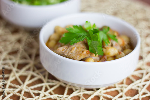 Chickpeas with meat in a white bowl with parsley