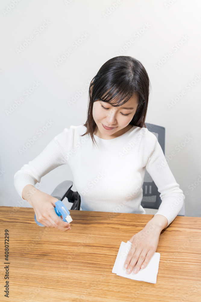 Woman disinfecting desk with alcohol Woman disinfecting desk with alcohol