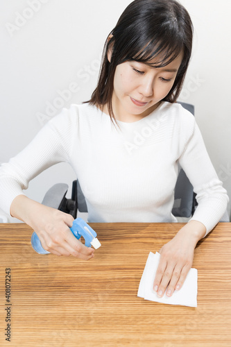 Woman disinfecting desk with alcohol