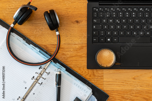 Smart working desktop with laptop, headset, agenda and coffee