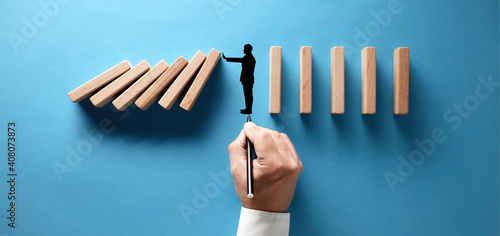 Businessman hand drawing silhouette of a man making a stop gesture to prevent wooden dominos from collapsing