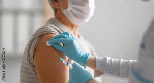Slika na platnu Doctor giving a senior woman vaccination