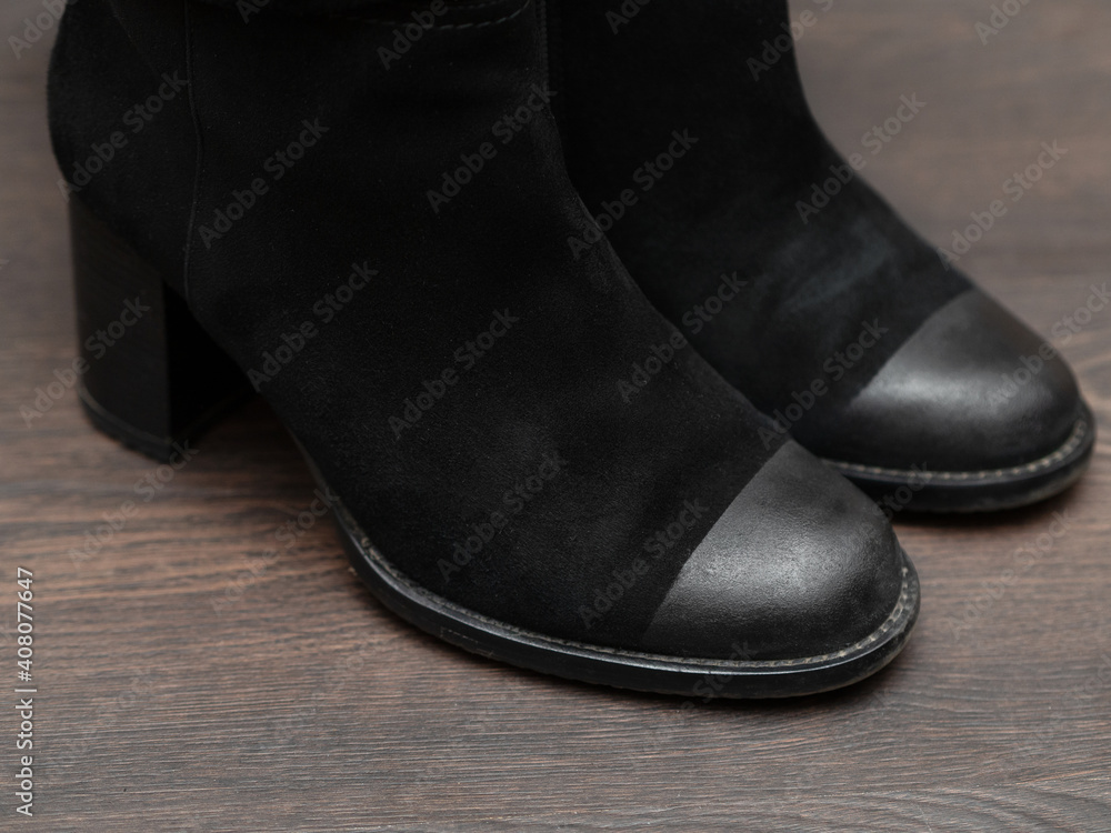 Women's black boots on a wooden background. Women's black boots on a wooden background.