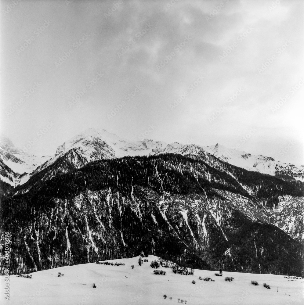 Obraz premium View of the Alpine mountain range in winter from the top of the village of Alvaneu in Switzerland, shot with black and white analogue film technique