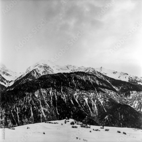 View of the Alpine mountain range in winter from the top of the village of Alvaneu in Switzerland, shot with black and white analogue film technique photo