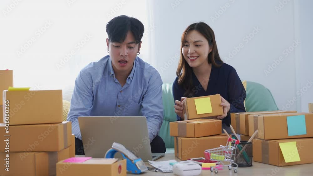 Happy business couple sit on sofa use laptop computer checking customer order shipping boxes Happy business couple sit on sofa use laptop computer checking customer order shipping boxes