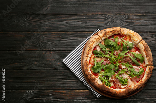 Tasty pizza with meat and arugula on black wooden table, top view. Space for text