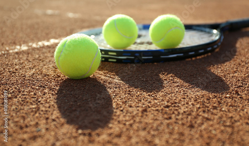 Tennis balls and racket on clay court © New Africa