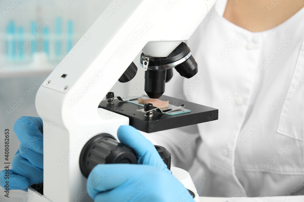 Scientist inspecting meat sample with microscope in laboratory, closeup. Poison detection Scientist inspecting meat sample with microscope in laboratory, closeup. Poison detection