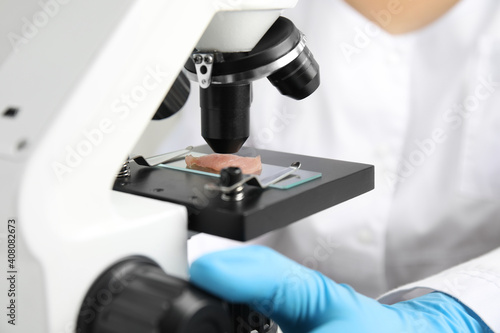 Scientist inspecting meat sample with microscope in laboratory, closeup. Poison detection