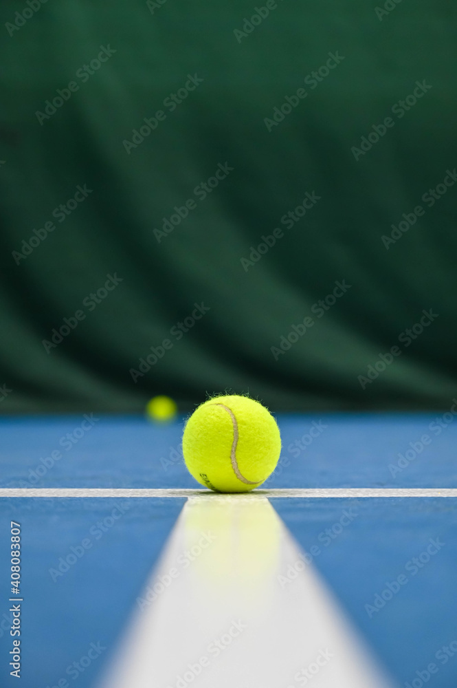 Close-up of tennis ball on blue hard court with white stripe.