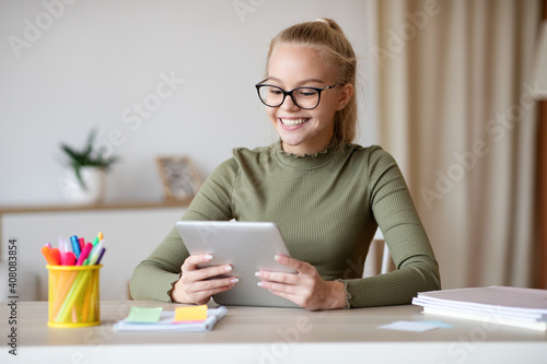 Cheerful teen girl looking at digital tablet screen