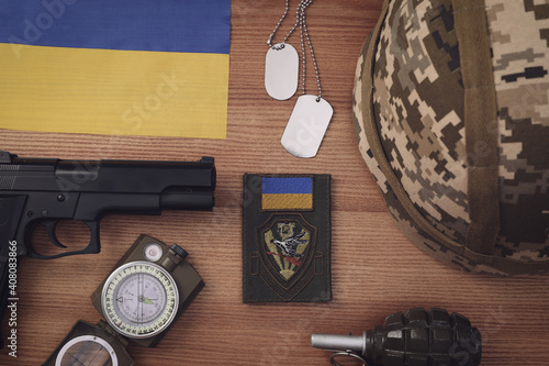 Tactical gear and Ukrainian flag on wooden table, flat lay