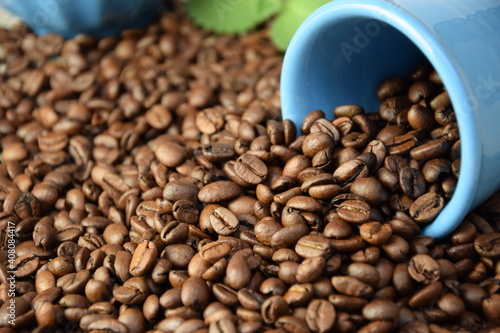 Coffee beans pouring out of a blue cup Roasted Arabica grain coffee background