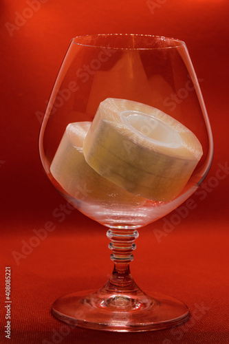 stationery tape in a glass goblet on an orange background