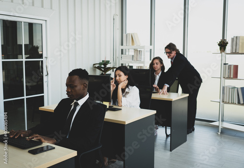 multiethnic businesspeople including man, woman, caucasian and african american people sitting at dest and working in internation corporate photo