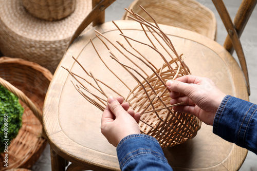 Bild auf Leinwand Woman weaving wicker basket indoors, closeup view
