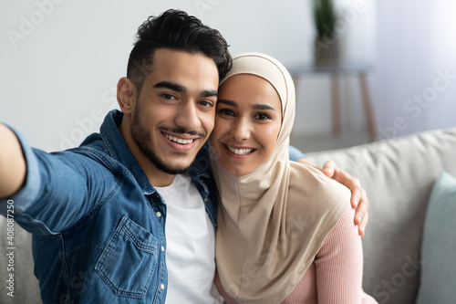 Beautiful muslim man and woman in hijab taking selfie