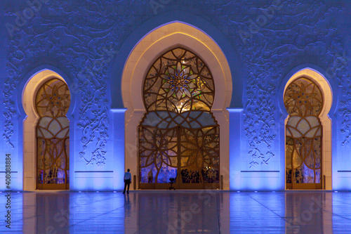 The beautiful big door and wall of Sheikh Zayed Grand Mosque at night. Eid Mubarek. Body guard is waiting outside the door. Entrance door of the mosque.