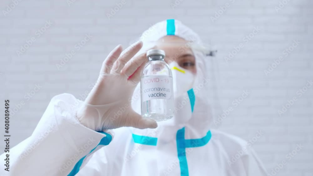 Medical worker in protective suit holding vaccine against coronavirus. Medical worker in protective suit holding vaccine against coronavirus.