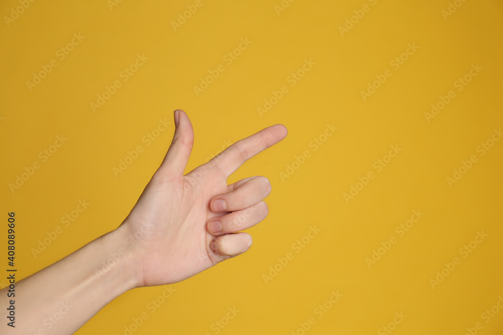 Naklejka premium Woman pointing at something on yellow background, closeup. Finger gesture