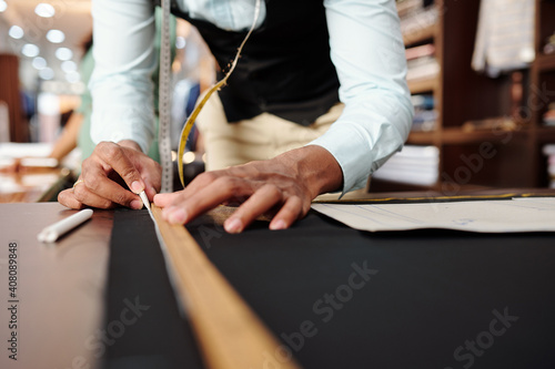 Fotografía Close-up image of tailor using wooden ruler and piece of chalk when drawing deta