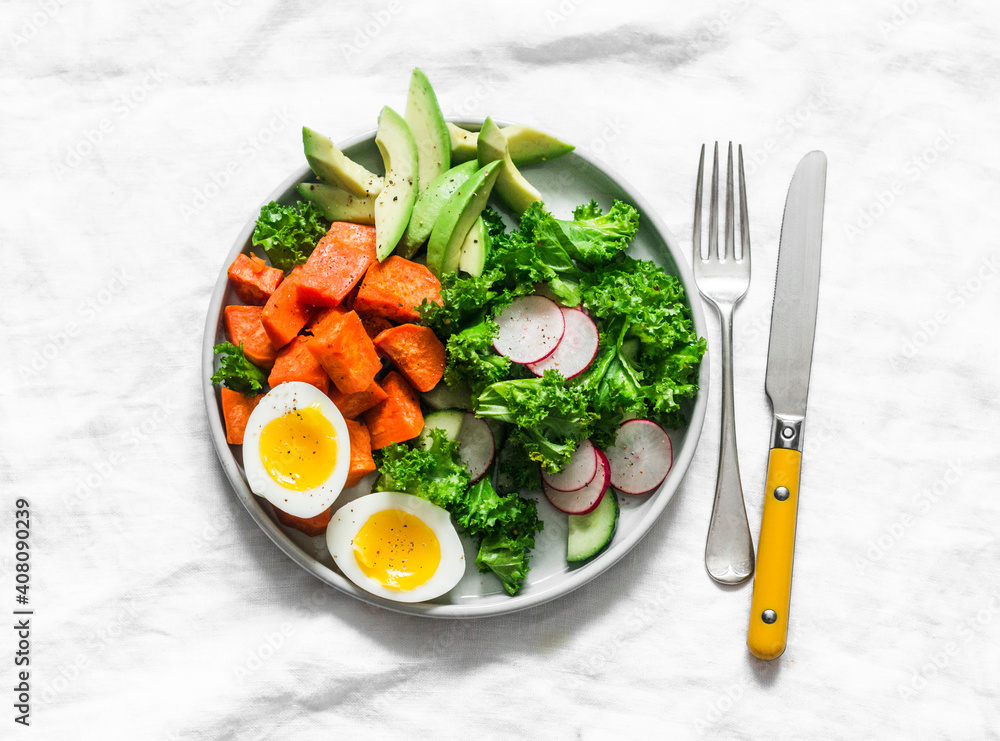 Vegetarian lunch - boiled sweet potatoes, egg, kale, avocado, radish, cucumber salad on a light background, top view Vegetarian lunch - boiled sweet potatoes, egg, kale, avocado, radish, cucumber salad on a light background, top view